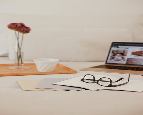 Close up of a notebook and glasses on a bright desk showing analog activities