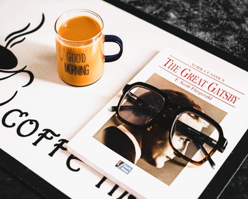 A cup of coffee and glasses resting on a table indicating a break