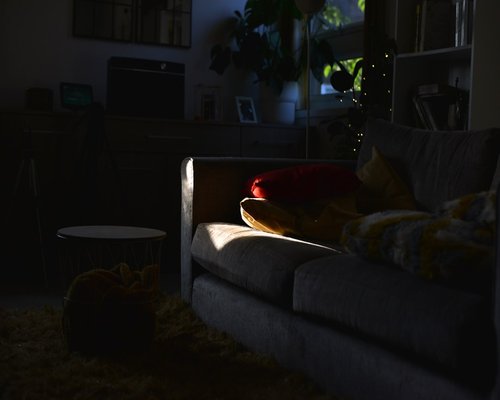 Person relaxing in a dimly lit room reading a physical book with a warm lamp